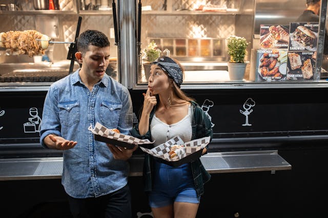 couple standing near the food truck and eating